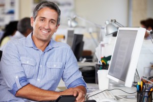 Man Working At Desk In Busy Creative Office